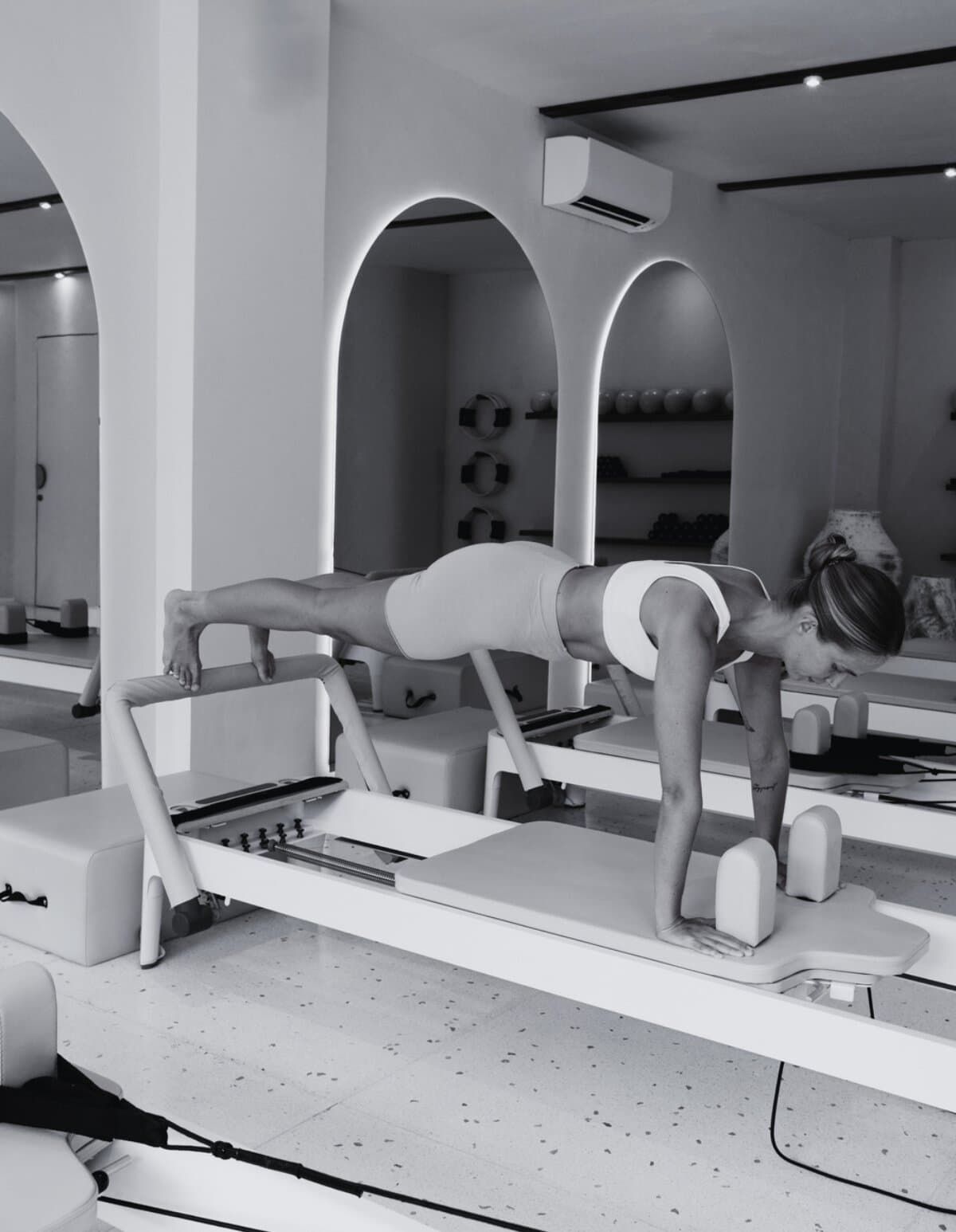 Athlete in a long plank position on a Pilates reformer footbar in a studio