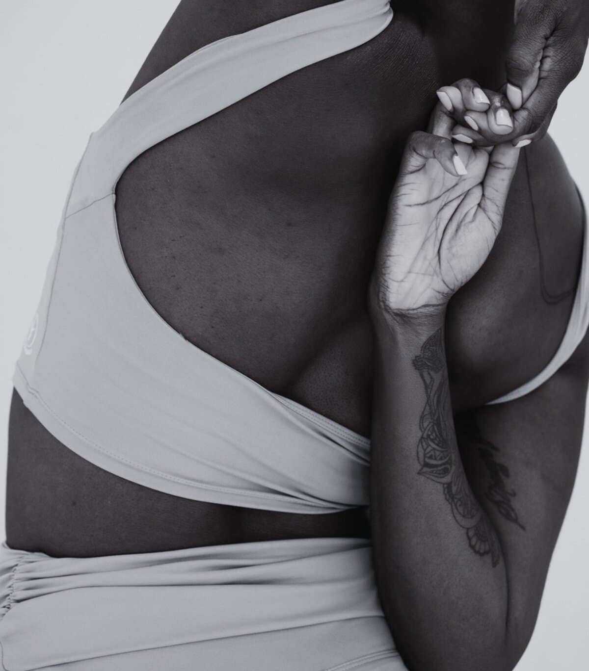 Black and white close up of arms and back in a gentle stretch or reach